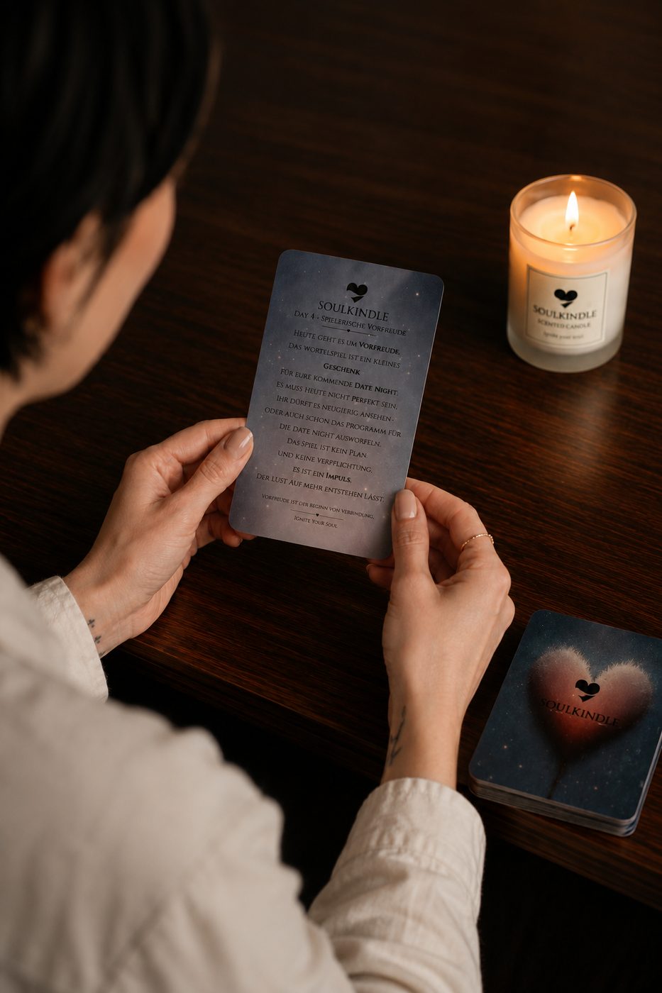 Person liest eine SoulKindle Tageskarte bei Kerzenlicht